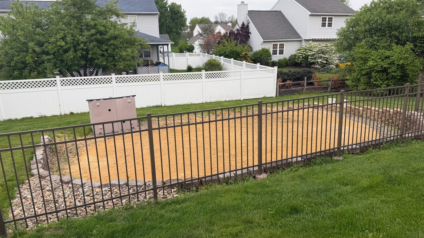 Clean gravel pad with iron railing fence after pool removal