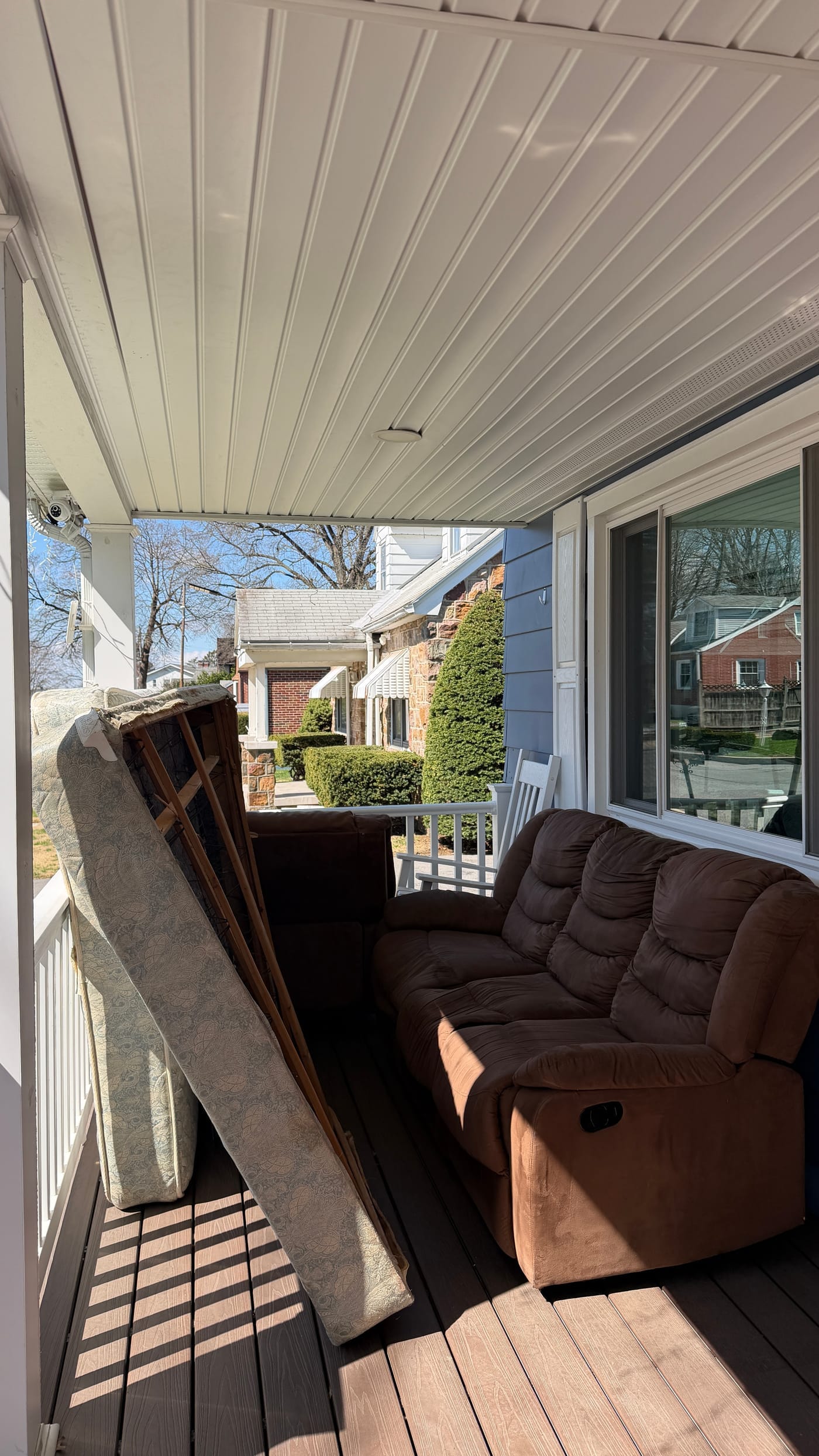 Old mattress and recliner cluttering a front porch before junk removal