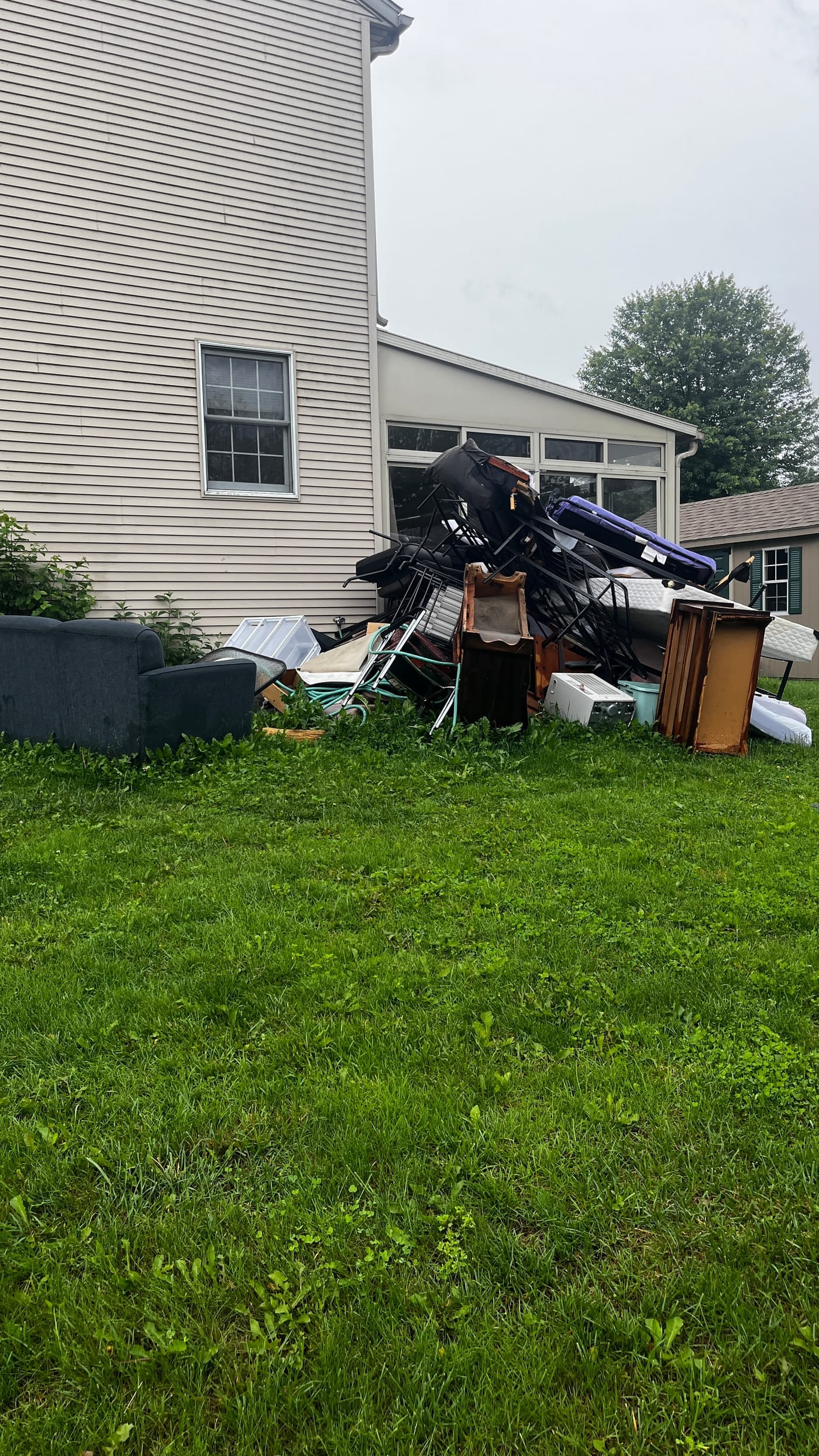 Large pile of outdoor furniture and debris by a sunroom